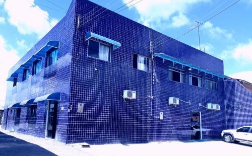 马塞约POUSADA OLÍMPIA的前面有一辆汽车停着的蓝色砖砌建筑