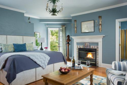BoyceL'Auberge Provencale Inn & Restaurant的一间卧室设有蓝色的墙壁、一张床和一个壁炉