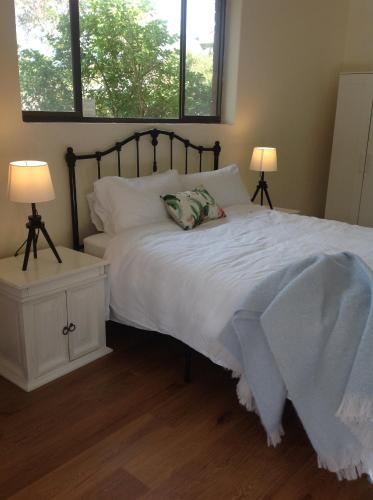 埃利奥特港Port Elliot rural retreat的一间卧室配有一张带白色床单和两盏灯的床。