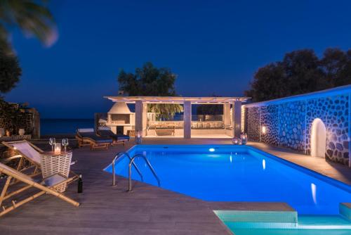 卡马利Damma Beachfront Luxury Villa的游泳池在晚上配有桌椅