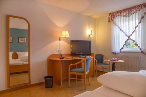Gädheim林德酒店的酒店客房配有一张床和一张书桌及一台电视