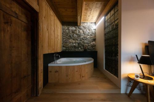 Savièse拉格德豪宅酒店的一间带浴缸的浴室,位于一个木墙客房内