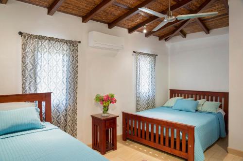 IguanaTown House 9的卧室内的两张床,配有蓝色的床单和鲜花