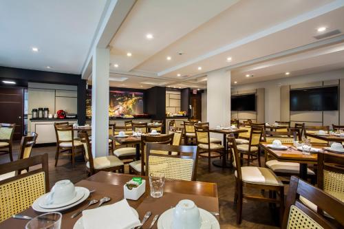 巴拉奈里奥-坎布里乌Santa Inn Hotel的一间带桌椅的餐厅和一间酒吧