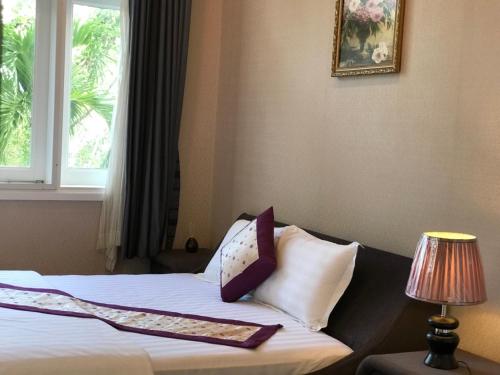 美奈Villa Mui Ne Phan Thiet的卧室配有带枕头的床铺和窗户。
