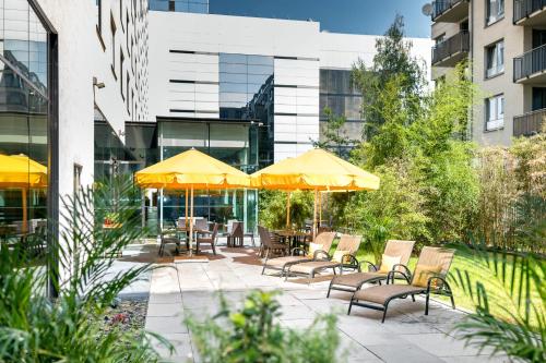 布拉格OREA Hotel Angelo Praha的庭院配有桌椅和遮阳伞。