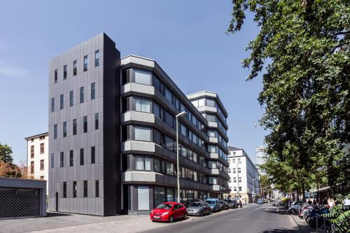 美因河畔法兰克福VISIONAPARTMENTS Gutleutstrasse - contactless check-in的街道上的建筑物,前面有车辆停放