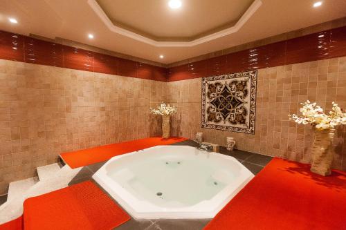 沙迦Red Castle Hotel的浴室铺有红色瓷砖,设有大浴缸。