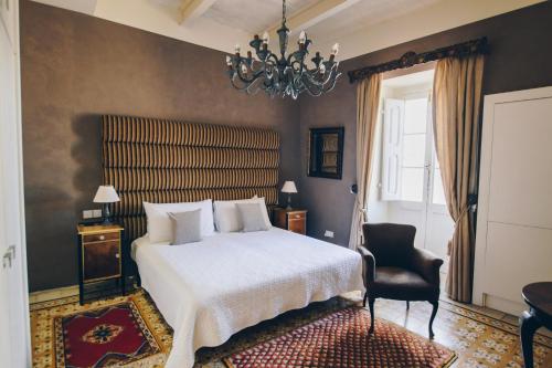 森格莱阿森格莱阿萨利港酒店的一间卧室配有一张床、一把椅子和一个吊灯。
