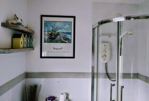 埃克斯茅斯Summerwind Guest House的带淋浴的浴室和墙上的照片
