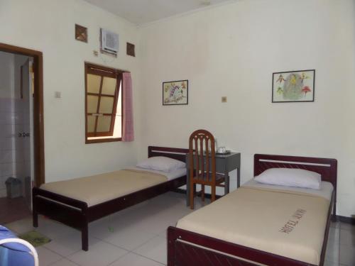 玛琅Armi Hotel Malang的客房设有两张床、椅子和桌子。