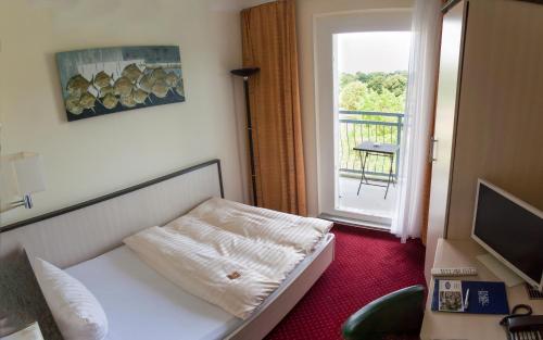 新勃兰登堡新勃兰登堡公园酒店的客房设有床、电视和窗户。