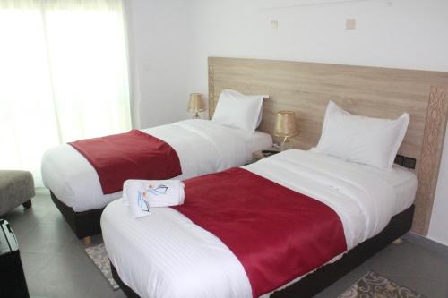 达赫拉Dakhla Sur Mer Hôtel的配有2张位于酒店客房的床,提供白色和红色床单