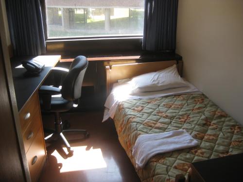 多伦多多伦多大学威尔逊霍尔酒店的一间卧室配有一张床、一张桌子和一把椅子