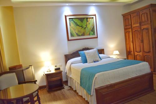 佩雷拉佩雷拉埃尔格兰酒店的一间卧室配有一张大床、一张桌子和一张桌子