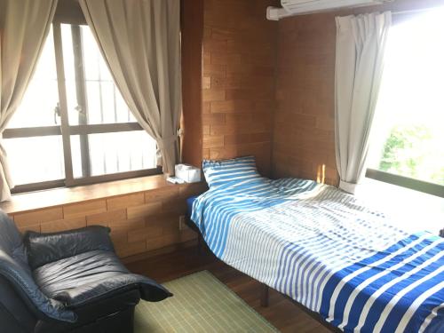 宫古岛我爱你民家宿旅馆的一间卧室设有两张床、一把椅子和窗户。