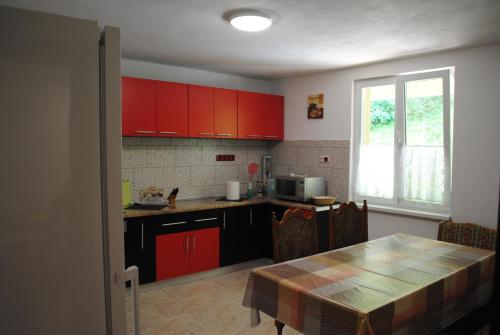 莫内亚萨Casa Flori de Nuc的厨房配有红色橱柜、桌子和窗户