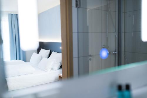 梅青根Hotel U7的一间卧室配有一张带白色枕头和镜子的床