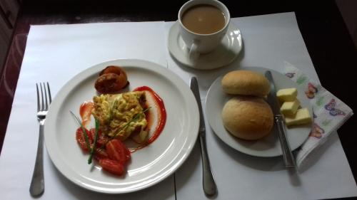 LungiAirport Lodge Lungi的餐桌,带两盘食物和一杯咖啡的桌子