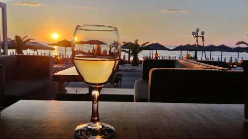 乐托卡亚Nefeli Apartments的坐在桌子上一边欣赏日落,一边品尝葡萄酒