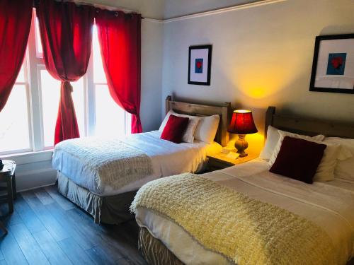 比斯比Hotel San Ramon的一间卧室设有两张床,窗户配有红色窗帘