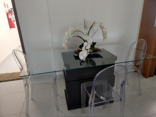 若昂佩索阿Essencial Manaíra的一张带两把椅子的玻璃桌和花瓶