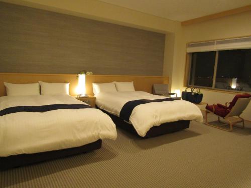 气仙沼市Japanese Style Hotel Isomura的酒店客房设有两张床和窗户。