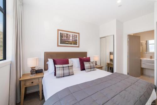 皇后镇Executive 2 Bedroom Apartment Remarkables Park的卧室配有带红色枕头的大型白色床