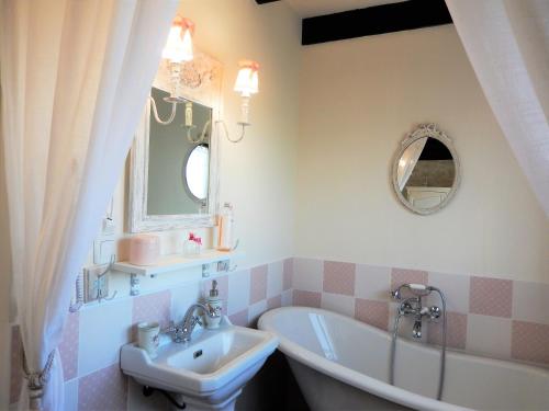 Réau拉科多讷瑞德利奥旅馆的一间带水槽、浴缸和镜子的浴室