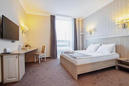 阿斯塔纳AYKUN Hotel by AG Hotels Group的酒店客房配有一张床、一张书桌和一台电视。