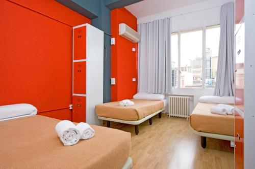 马德里马德里运动旅馆的客房设有两张带橙色墙壁和窗户的床。