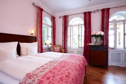 NiederpöckingLA VILLA am Starnberger See的一间卧室配有一张带红色窗帘的大床