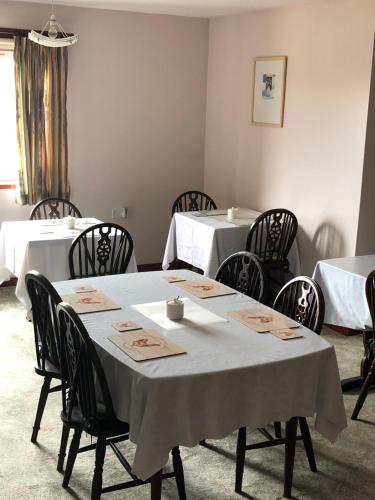 彼得黑德Invernettie guesthouse的用餐室配有白色桌子和黑色椅子