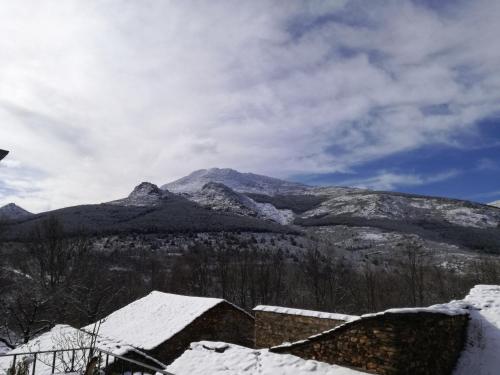 巴尔韦尔德德洛萨罗约斯Casa Rural Los Robles的山中满是雪,有房子和树木