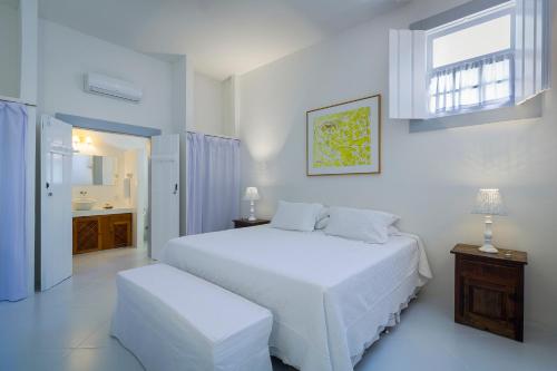 帕拉蒂Pousada Casa de Paraty的白色的卧室设有白色的床和窗户。