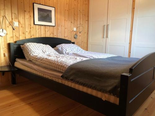 勒罗斯Svenskveien 23b的卧室内的一张床铺,设有木墙