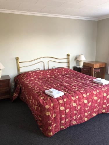 朗伊奥拉莉莉布鲁克汽车旅馆的一间卧室配有一张红色棉被的床