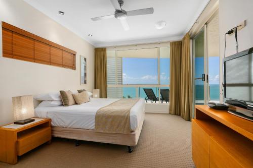 三一海滩三一海滩贝尔维尤酒店的一间卧室配有一张床、一台电视和一个阳台