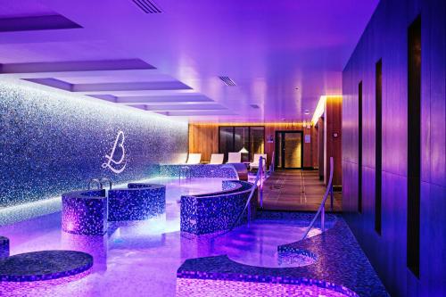 索略瑞莱斯伯纳德洛伊瑟酒店的酒店大堂设有紫色灯光和酒吧凳子