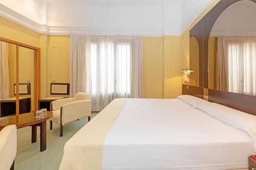赫雷斯-德拉弗龙特拉Hotel Soho Boutique Jerez的酒店客房设有一张大床和一张书桌。