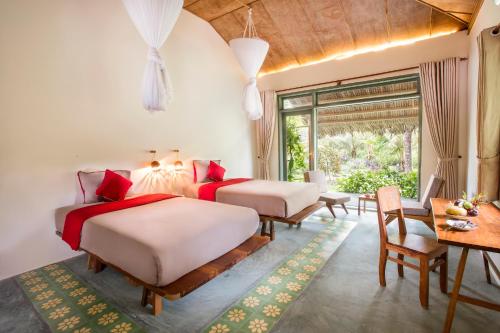 槟知湄公河之家民宿 的一间卧室配有两张床和一张桌子及椅子