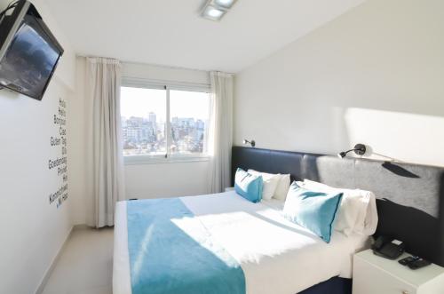 布宜诺斯艾利斯坎雷可乐塔酒店的一间卧室配有一张带蓝色枕头的床和一扇窗户。
