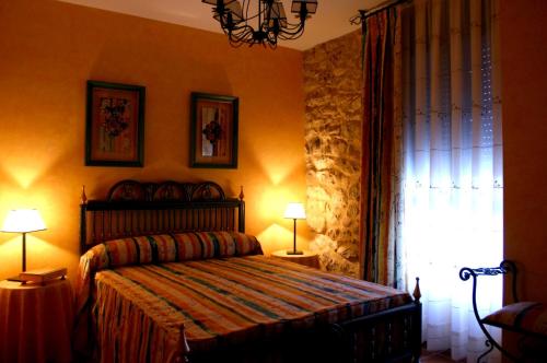 布尔戈斯Casa Rural Valle Esgueva的一间卧室配有一张带两盏灯的床和一扇窗户。