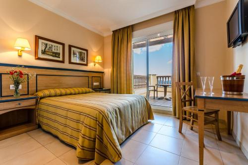 阿尔赫西拉斯米拉多尔酒店的酒店客房设有一张床、一张书桌和一个阳台。
