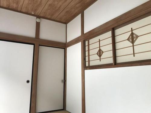 松崎町丝川旅馆的一间白色墙壁、木制天花板和门的客房