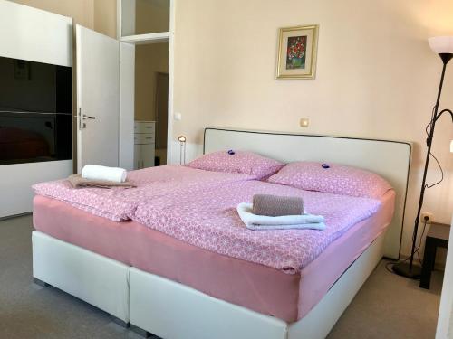 普图伊Apartments Terme Ptuj的一间卧室配有粉红色的床和毛巾