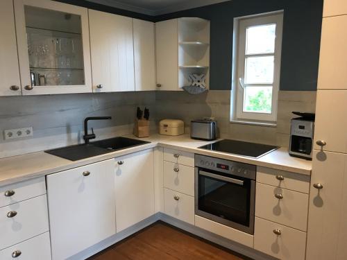 格洛韦Ferienwohnung Lilly的厨房配有白色橱柜、水槽和窗户。