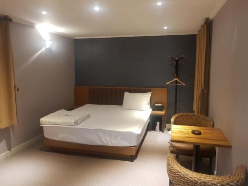 釜山阳光汽车旅馆的卧室配有1张床、1张桌子和1把椅子