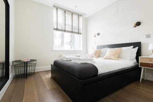 伦敦The Oxford Street Studio - 1BDR in Paddington的一间卧室配有一张带黑色床头板的床和窗户