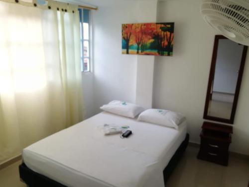 佛罗里达布兰卡Hotel Avenida El Bosque的一间卧室配有一张带白色床单和镜子的床